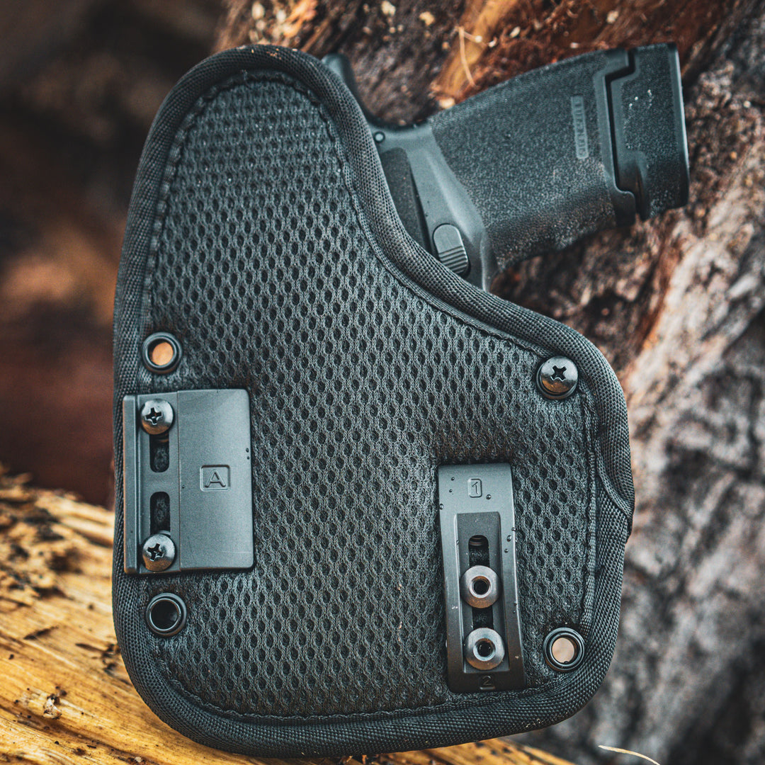 OMNIcarry holster retention plates and mesh backer displayed with pistol installed, demonstrating adjustable holster retention design.